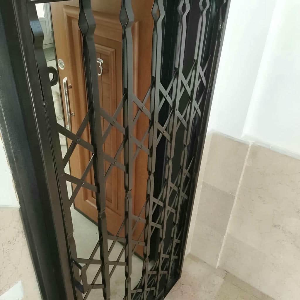 جزئیات پوشش حفاظ درب آکاردئونی خاکستری کنار دیوار نمناک