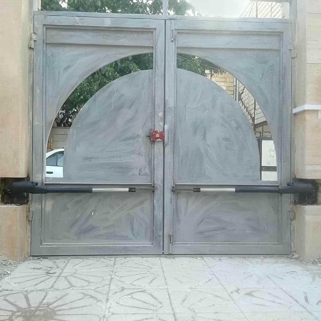 جک بازویی مشکی روی درب حیاط فلزی